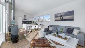 A modern living space with a kitchen, dining area, and a large window with a sailboat view.