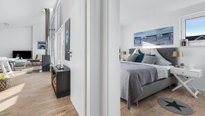 A modern bedroom with a bed, bedside tables, and a large window.