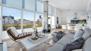 A modern living room with a fireplace, large windows, and a view of the neighborhood.
