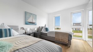 A modern bedroom with two beds, a desk, and a large window. - Lovely apartment in Olpenitz with sauna (Olpenitz)