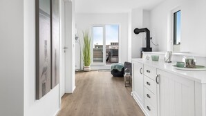A modern kitchen with white cabinetry, a black range hood, and a view to the outdoor patio. - Lovely apartment in Olpenitz with sauna (Olpenitz)