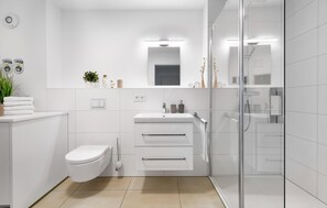 Ein modernes Badezimmer mit Toilette, Waschbecken und Dusche.