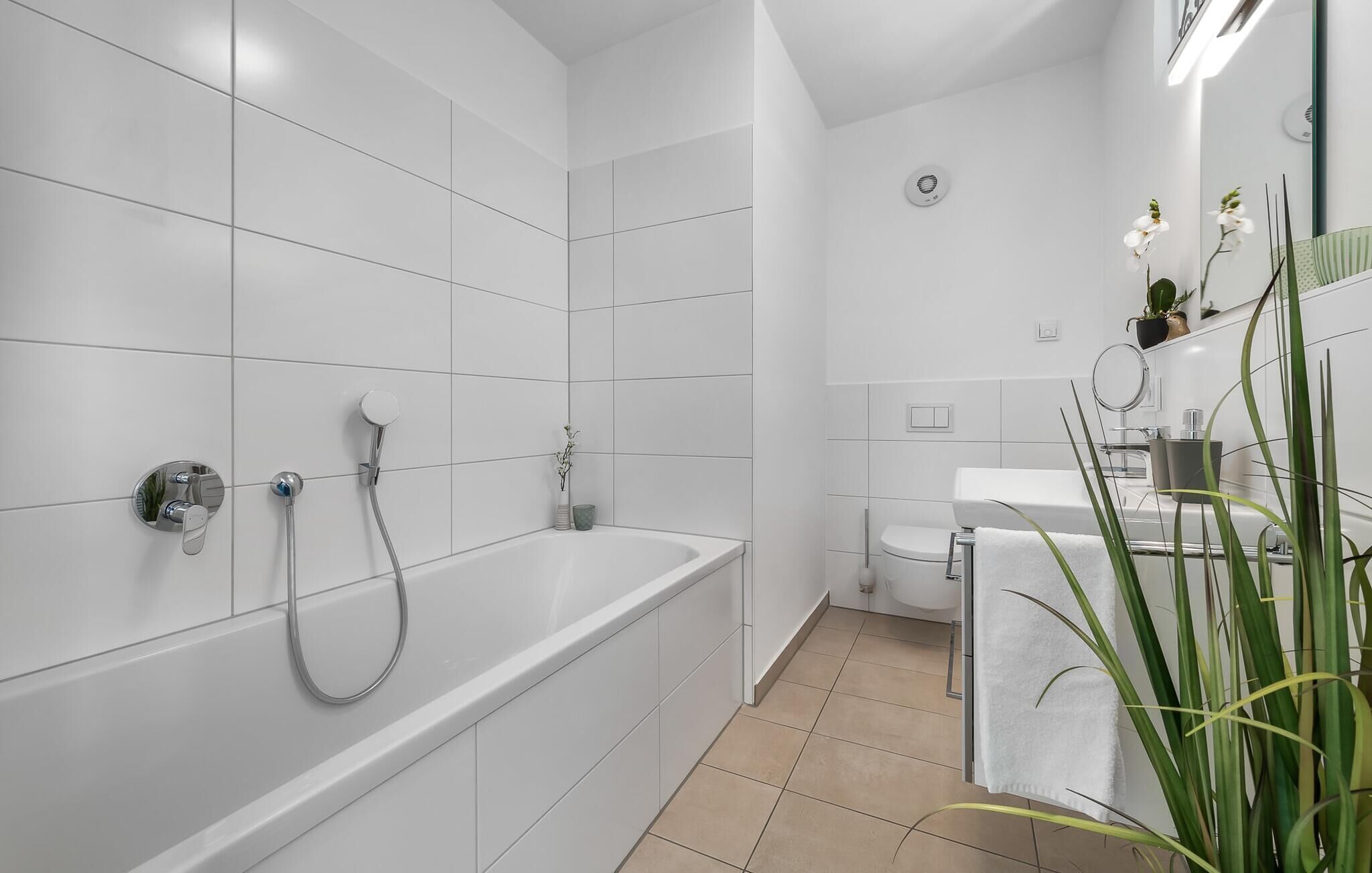 A modern bathroom with a bathtub, shower, toilet, and sink.