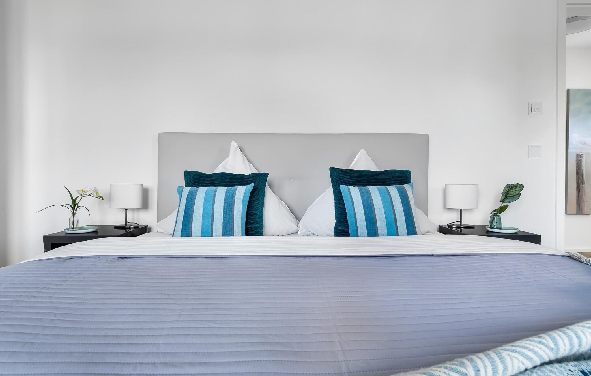 Ein Hotelzimmer mit einem großen Bett, zwei Nachttischen mit Lampen und einem Gemälde an der Wand.