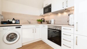 A modern kitchen with a Bosch washing machine, a Bosch oven, a microwave, and a coffee maker.