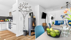 Une cuisine moderne avec des meubles blancs, une cuisinière noire et un motif d’arbre décoratif sur le mur.
