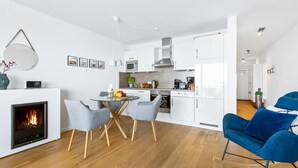 A modern kitchen with white cabinets, a dining area with a round table, and a blue armchair. - Pet friendly apartment in Olpenitz (Olpenitz)