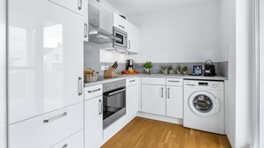 A modern kitchen with white cabinets, stainless steel appliances, and a built-in washing machine.