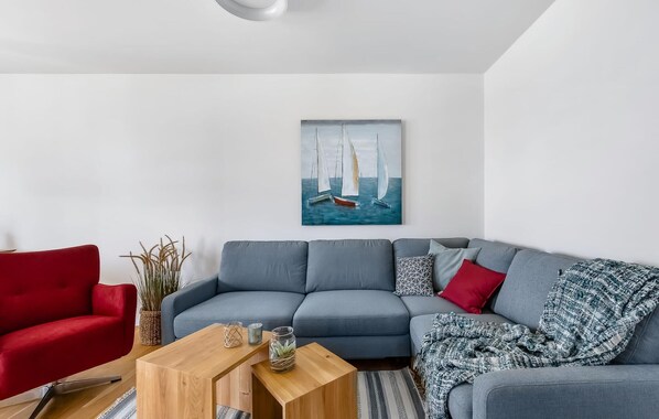 A modern living room with a grey sofa, a red armchair, and a wooden coffee table. - Beautiful apartment in Olpenitz (Olpenitz)