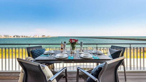 A table set for dining with a view of the sea and a distant pier. - Beautiful apartment in Olpenitz (Olpenitz)