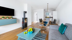A modern living room with a fireplace, a dining area, and a kitchen in the background. - Beautiful apartment in Olpenitz (Olpenitz)
