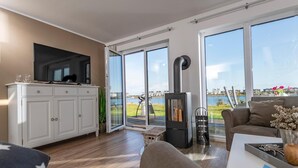 Ett modernt vardagsrum med en TV, vita skåp, en soffa och en öppen spis.