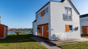 Ett tvåvåningshus med en träveranda, en liten farstu och utsikt över vattnet.