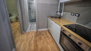 Eine kleine Küche mit einer Holzausziehtafel, einem Einbauofen und einem Geschirrspüler.