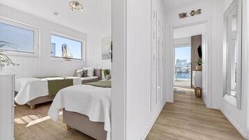 Hotelkamer met twee bedden, uitzicht op zee, een 'Welcome'-bord en een plant.