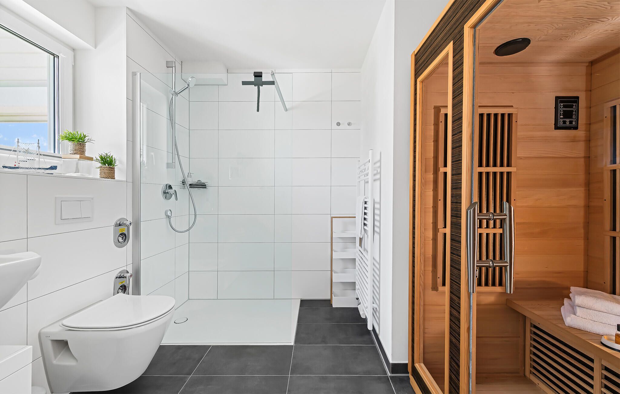 Et moderne badeværelse med bruser, toilet og et saunaområde.