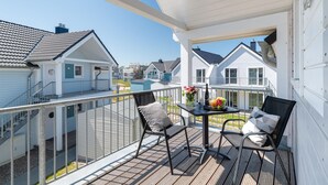 Un balcon avec deux chaises et une table, donnant sur une rangée de maisons similaires.