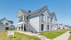 Une maison à deux étages dotée d’un balcon, d’un porche couvert et d’un escalier menant à l’étage supérieur.