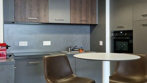Une cuisine moderne avec deux tabourets, une table blanche et un luminaire suspendu.
