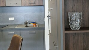 Une cuisine moderne avec des meubles gris, une chaise marron et une étagère ornée d’objets décoratifs.