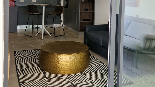 Un espace de vie moderne avec une porte-fenêtre coulissante donnant sur une cuisine et un coin repas.