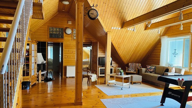 A spacious loft with wooden floors, a loft bed, a sofa, and a dining table.