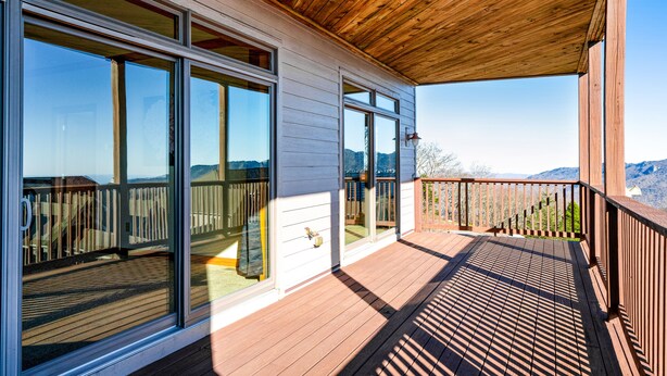 A wooden deck with large sliding glass doors and a view of the mountains. - Comfy Condo At Top Of Sugar Mtn - Ski In Ski Out - AC, WiFi (Sugar Mountain)