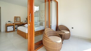 Ein modernes Schlafzimmer mit Glastür, einem Bett, einem Schreibtisch und Korbstühlen.