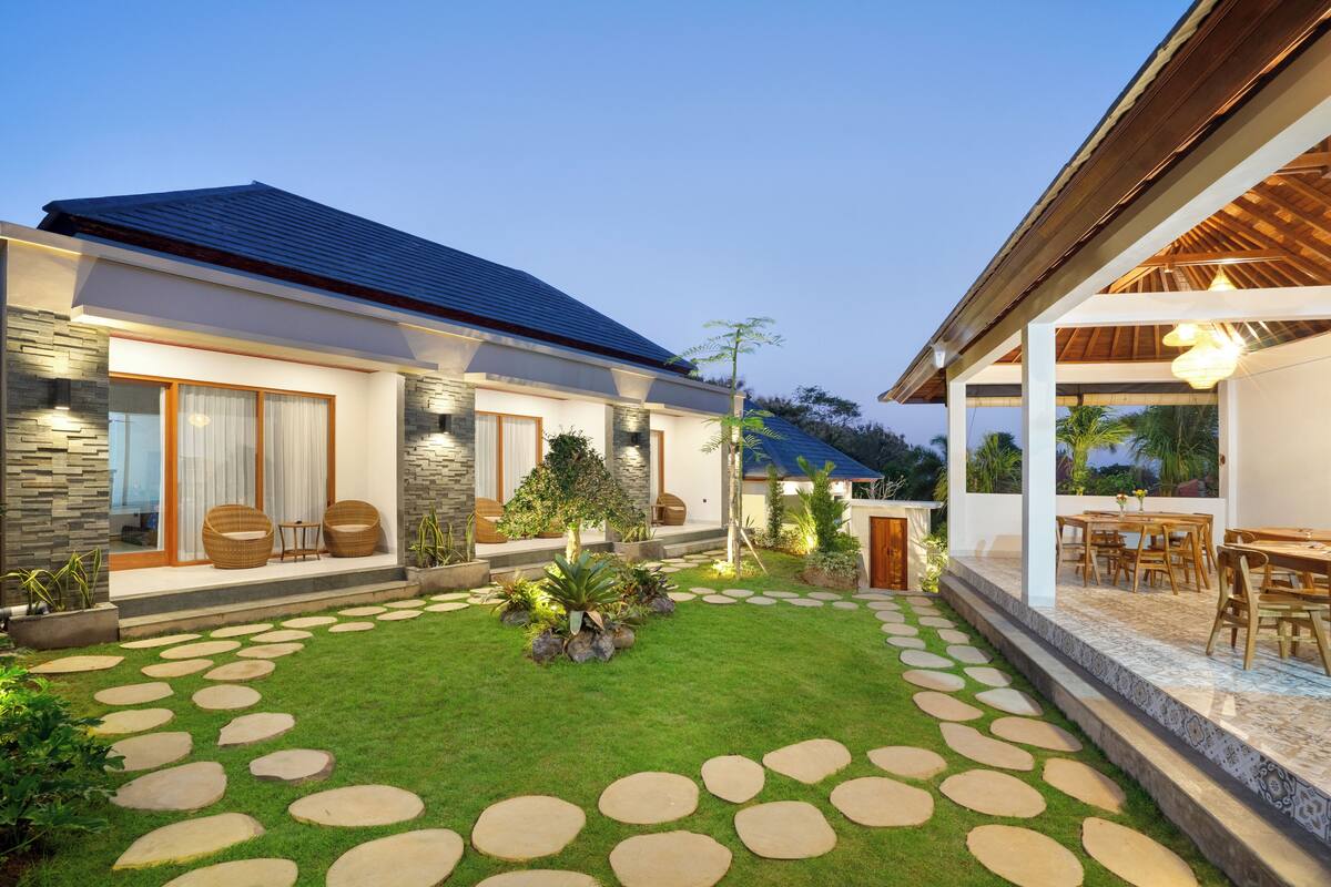 A modern house with a stone facade, a well-maintained lawn, and a patio area with outdoor furniture.
