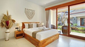 Ein geräumiges Schlafzimmer mit einem großen Bett, einem Holzkopfteil, Nachttischen und Blick auf den Garten durch eine Schiebetür.