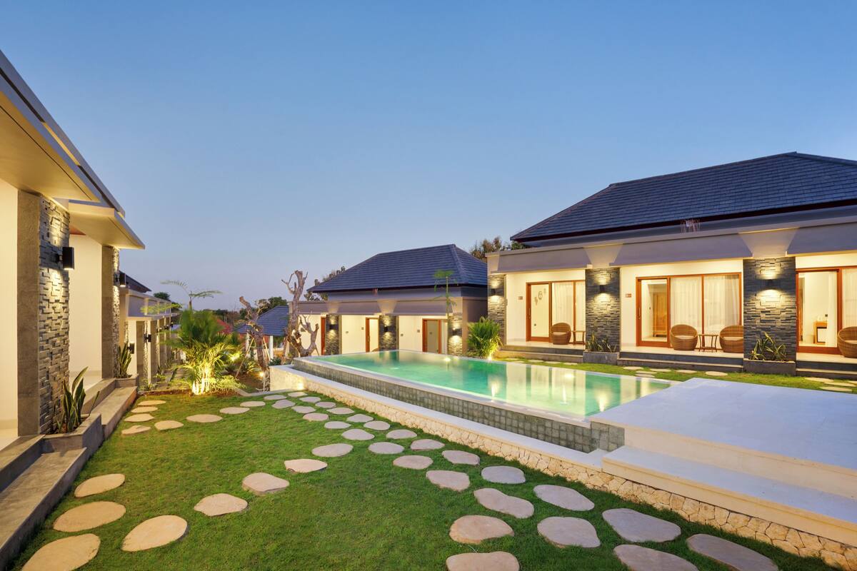 A modern house with a swimming pool, stone pathway, and a well-maintained lawn.