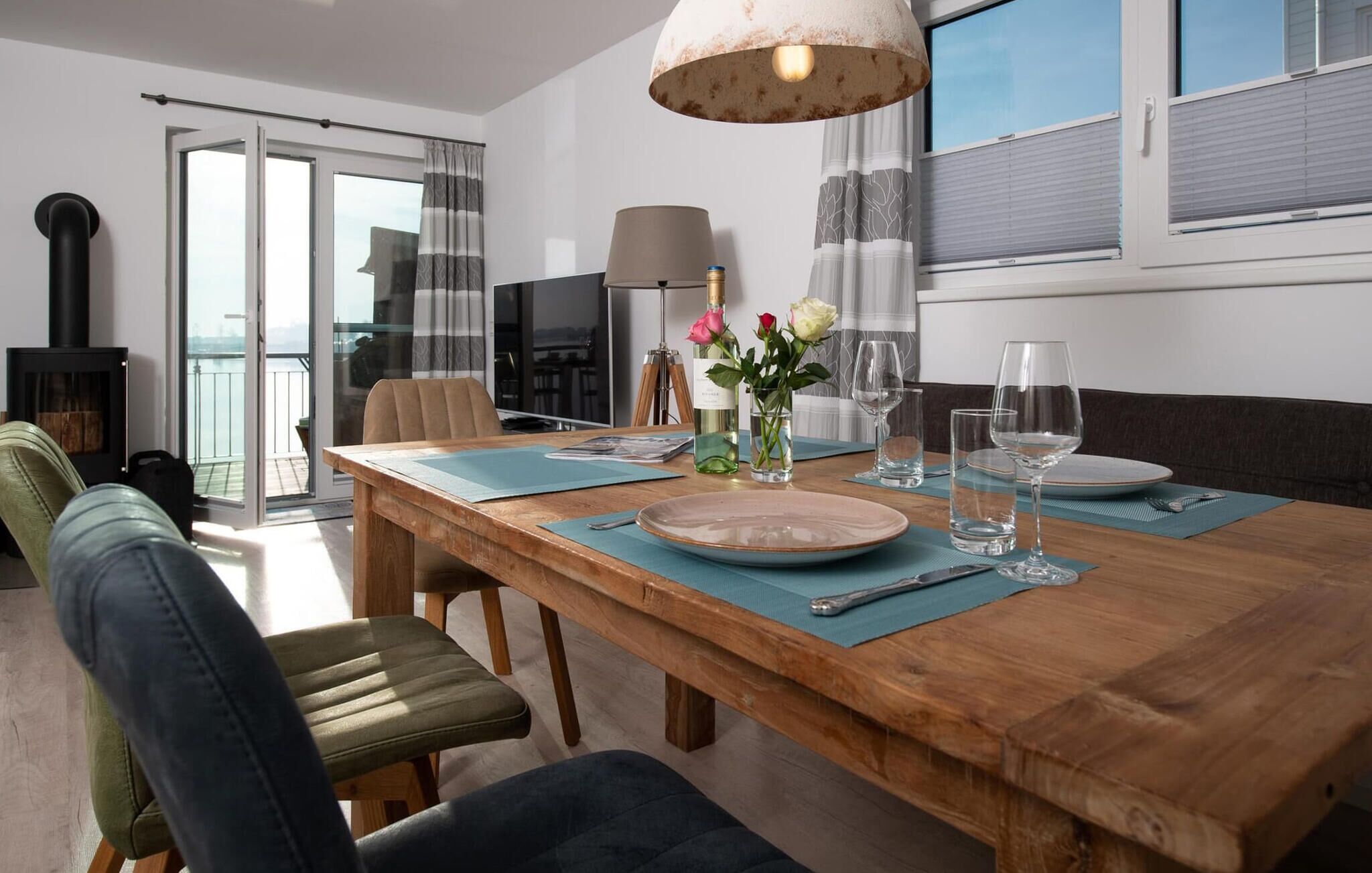 A dining area with a wooden table set for two, a sofa, and a fireplace.