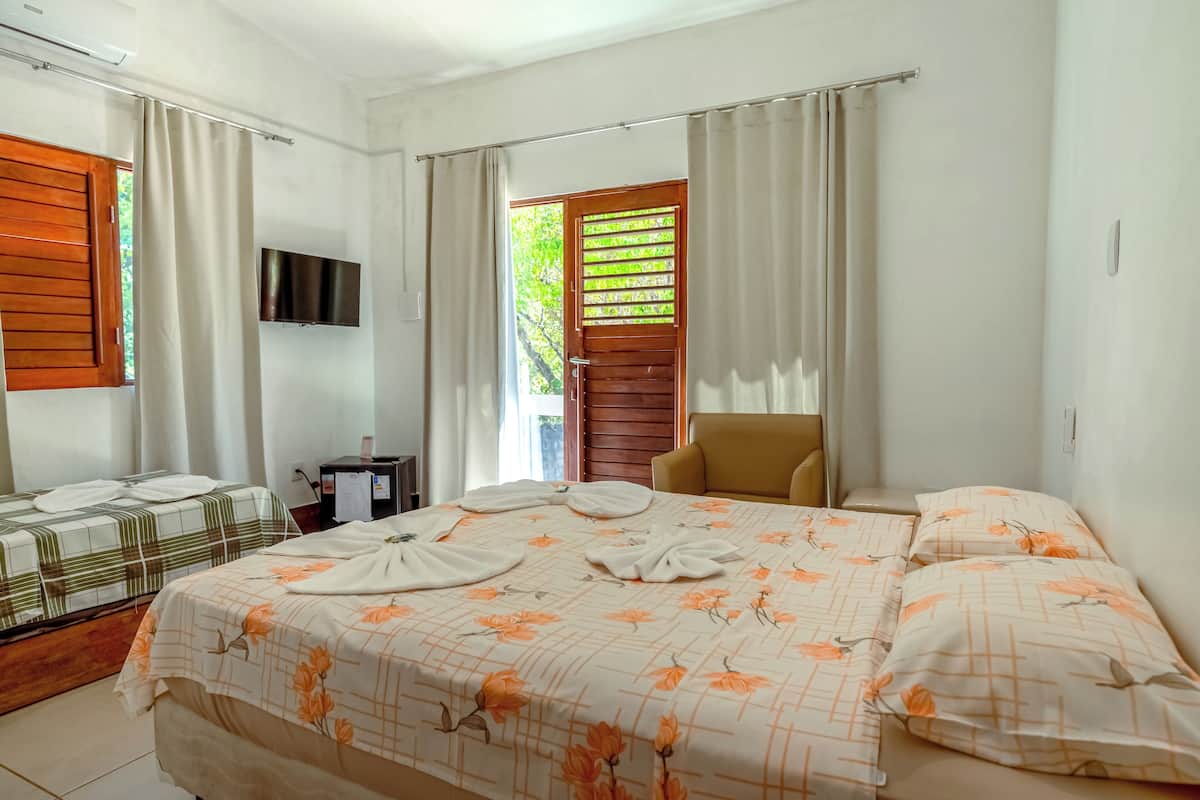 A hotel room with a large bed, a TV mounted on the wall, a wooden door, and a chair.