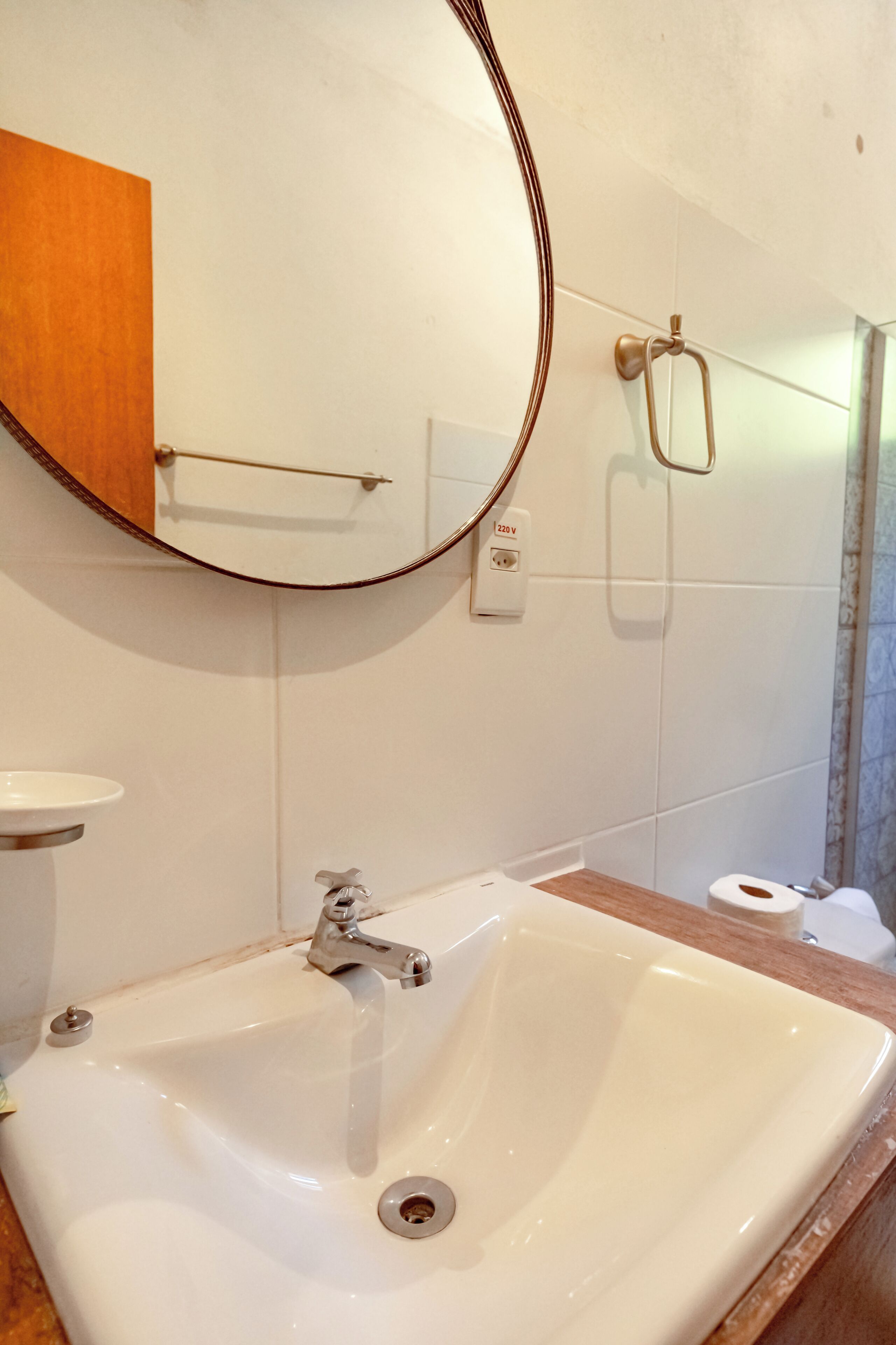 Un baño con un lavabo blanco, un espejo y un perchero para toallas.