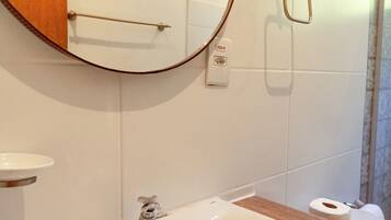 Un baño con un lavabo blanco, un espejo y un perchero para toallas.