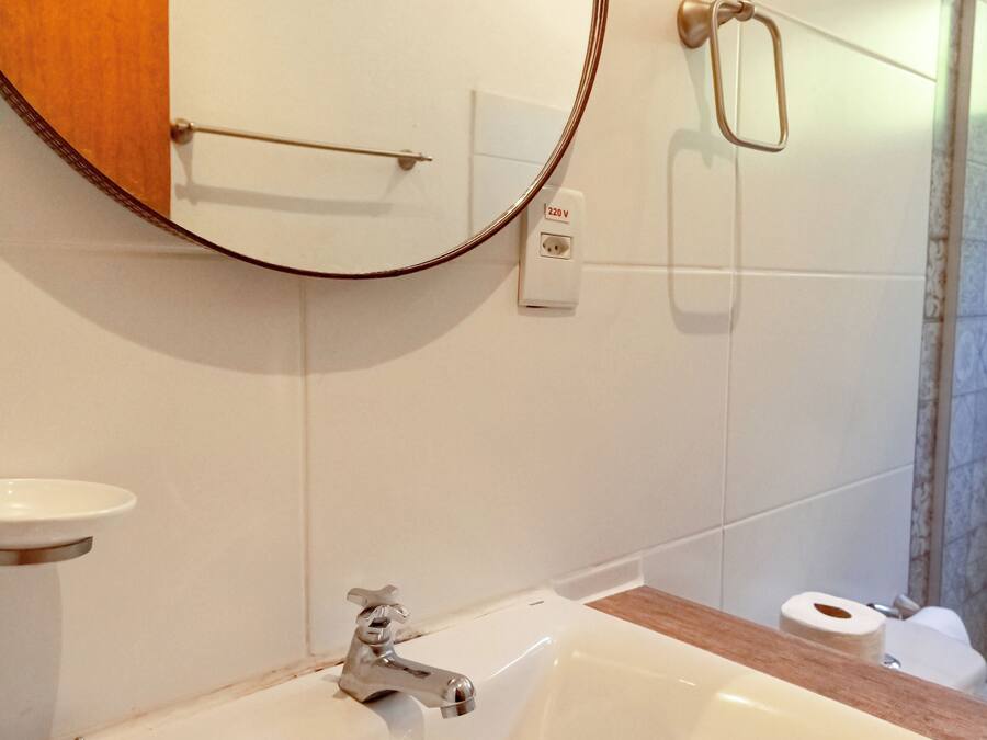 Un baño con un lavabo blanco, un espejo y un perchero para toallas.