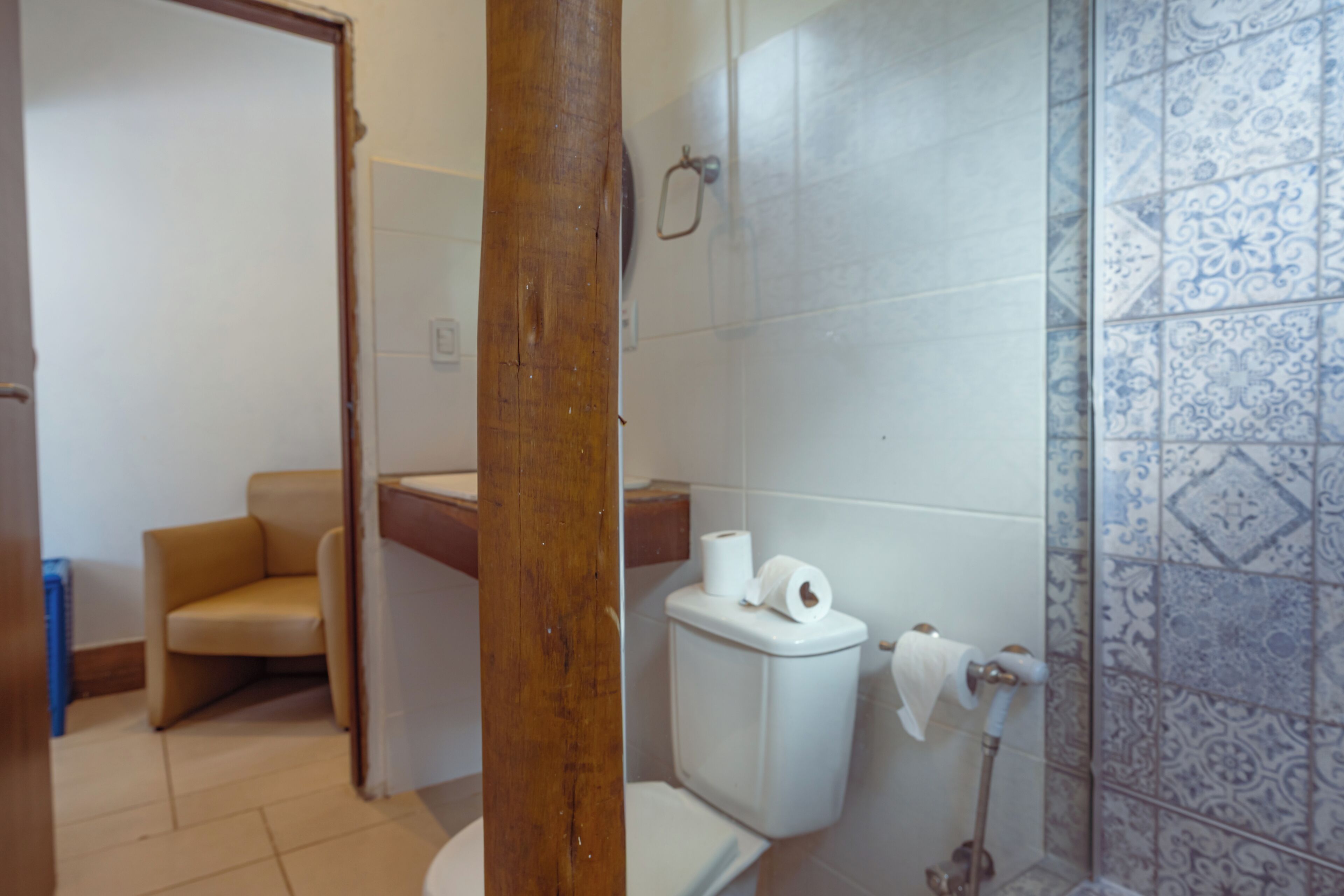 A bathroom with a toilet, a towel rack, and a patterned tile wall.