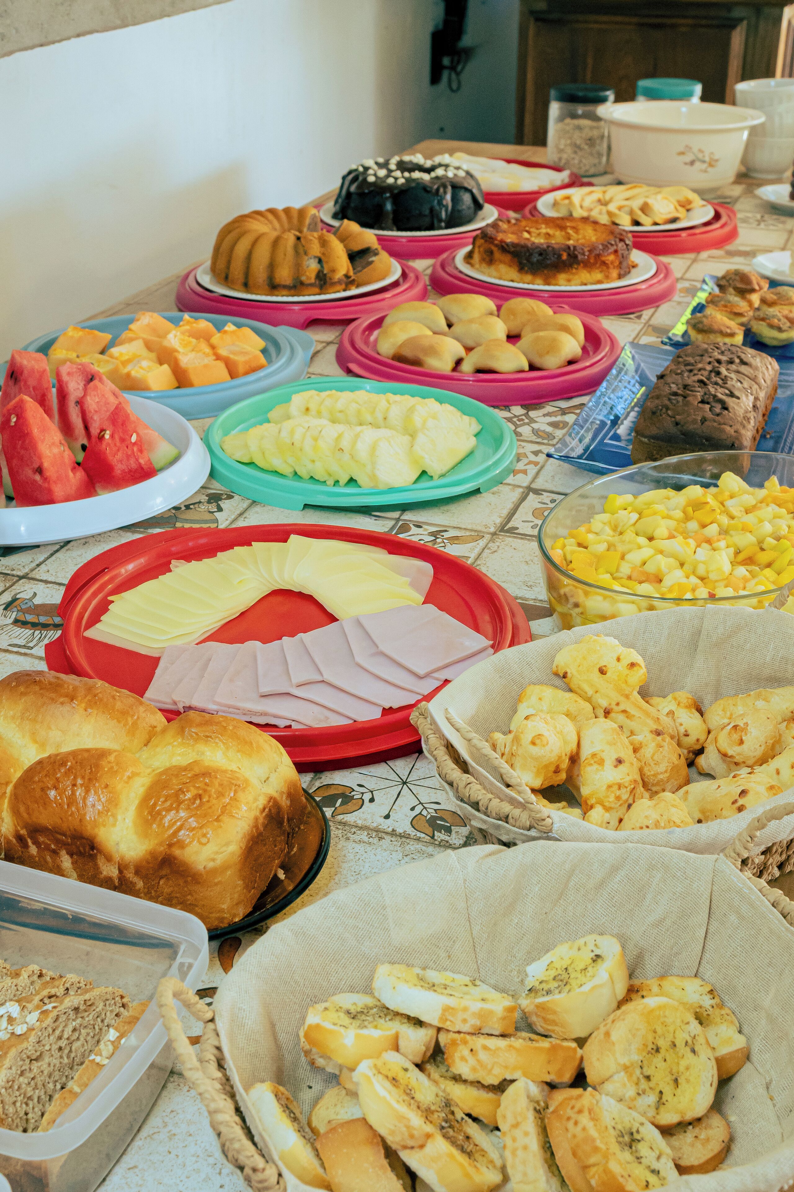 A buffet table with various food items including fruits, pastries, and bread.