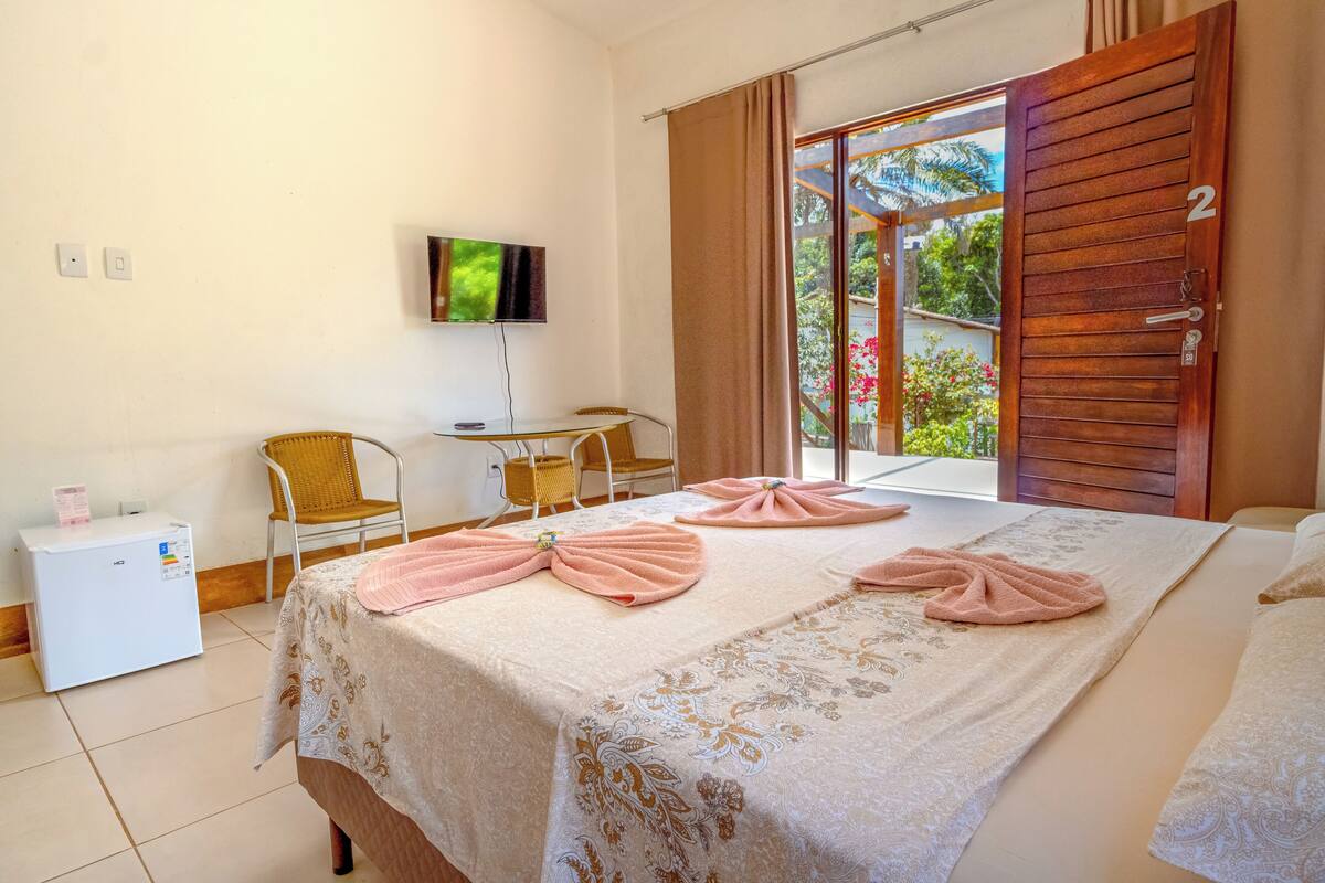 A hotel room with a bed, a TV, a small table, and a chair.