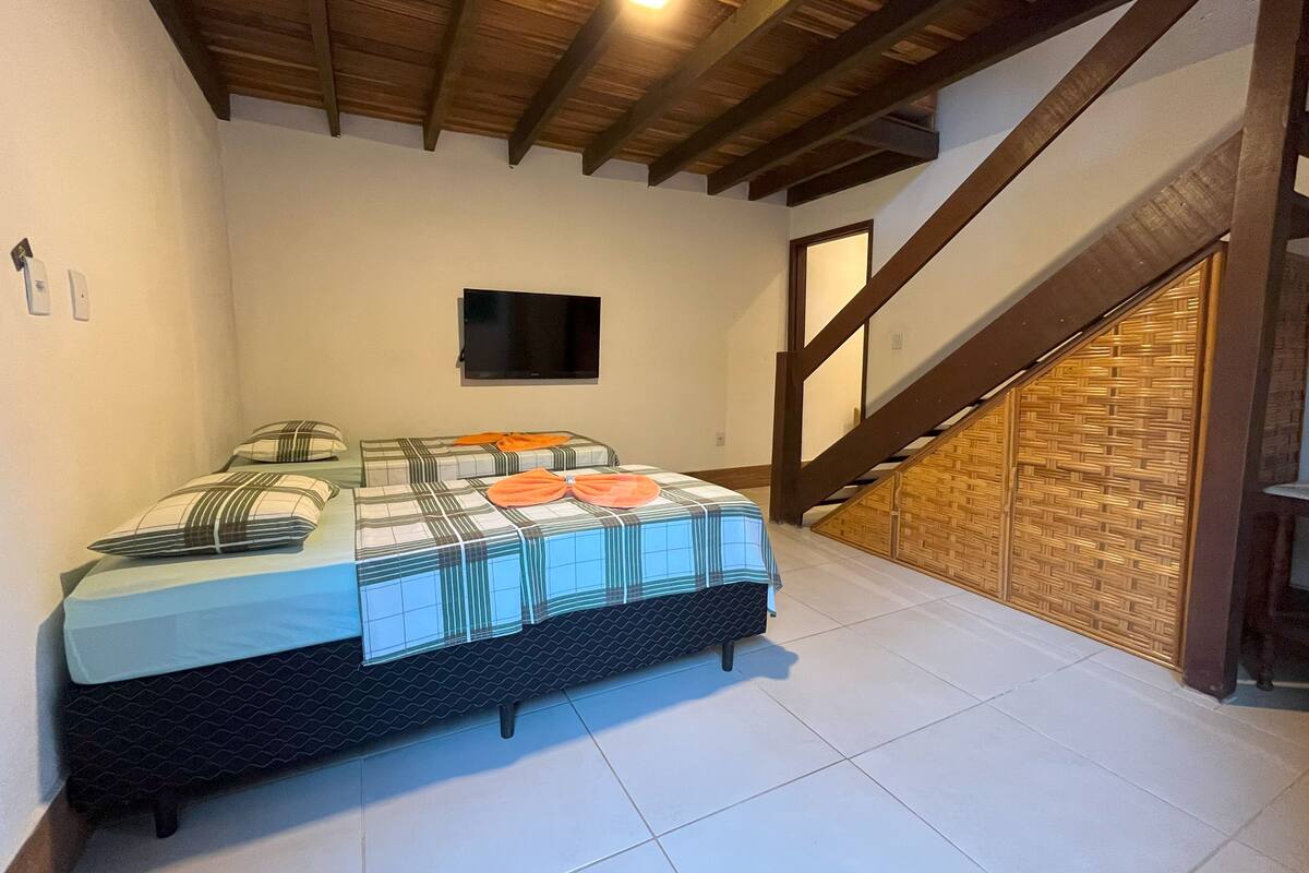 A bedroom with a bed, a TV, and a staircase.