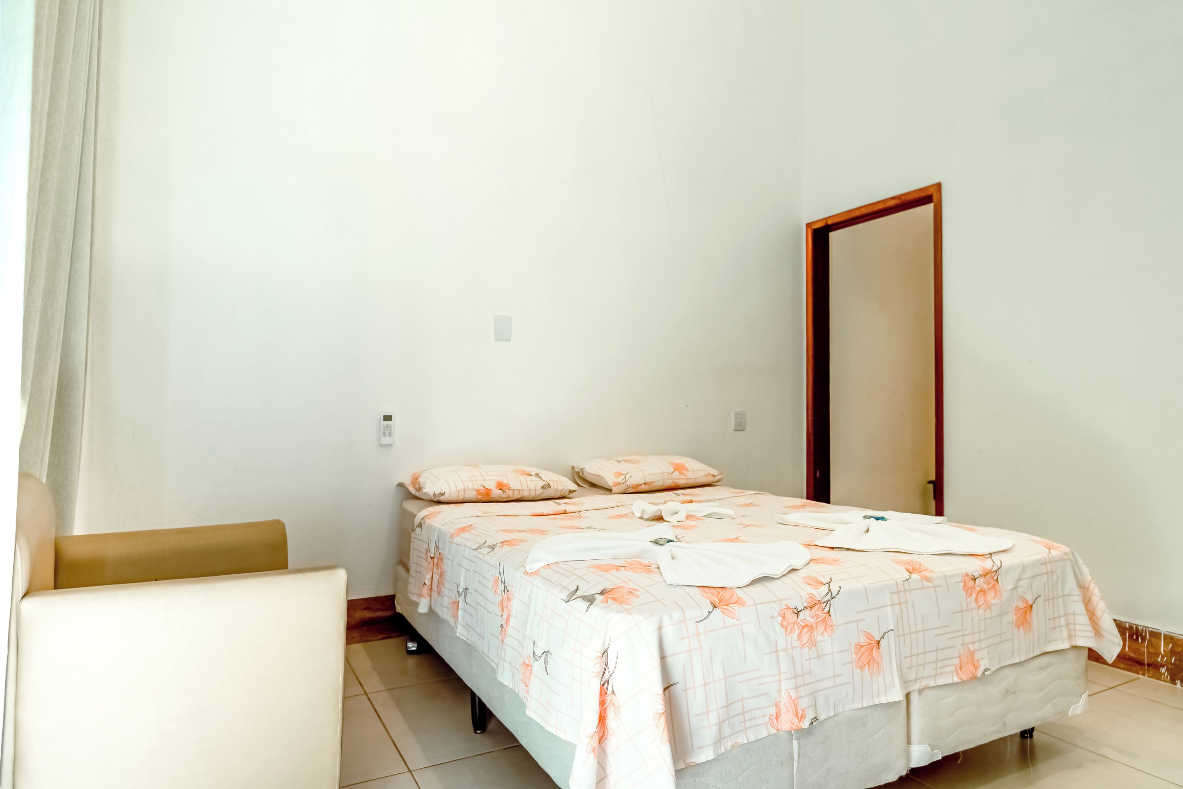 A bedroom with a bed, a chair, and a door.
