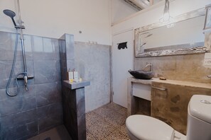 Une salle de bain équipée d’une douche, de toilettes, d’un lavabo et d’un miroir décoratif.