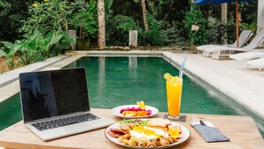 A laptop, breakfast, and a poolside setting with lounge chairs and umbrellas. - Daysha Ubud (Ubud)