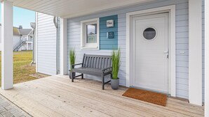 Un porche avec un banc, une porte et une boîte aux lettres.