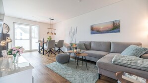 Un salon moderne avec un canapé gris, une table basse et un coin repas comprenant des chaises et une table.