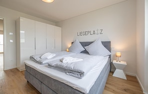 A modern bedroom with a bed, grey bedding, a grey headboard, and a wall-mounted sign reading "LIEGEPLATZ". - Nice apartment in Olpenitz with sauna (Olpenitz)