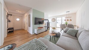 Un salon moderne avec un canapé, un téléviseur et une cheminée.