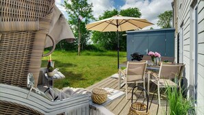 A patio with wicker furniture, a table with chairs, a grill, and a covered area with an umbrella.