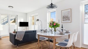 A modern dining area with a round table, white chairs, and a black pendant light.