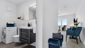 A modern apartment with a washing machine, a sink, and a chair. - Stunning apartment in Olpenitz (Olpenitz)